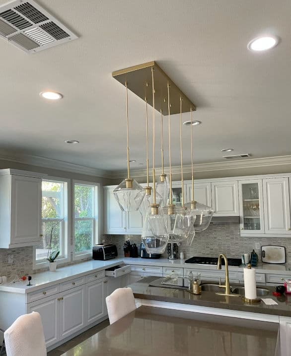 Modern kitchen with pendant lights, white cabinetry, and a sleek countertop design.