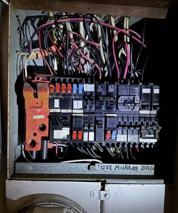 Electrical panel with circuit breakers and wiring, showcasing home electrical system setup.