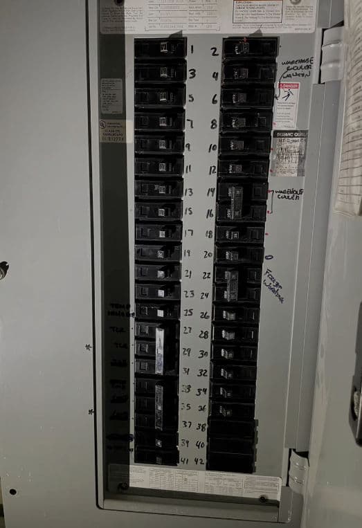 Electrical panel with labeled circuit breakers and notes for each circuit's purpose.