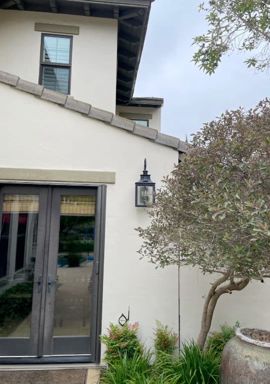 Exterior view of a house featuring a decorative lantern, potted plants, and a window.