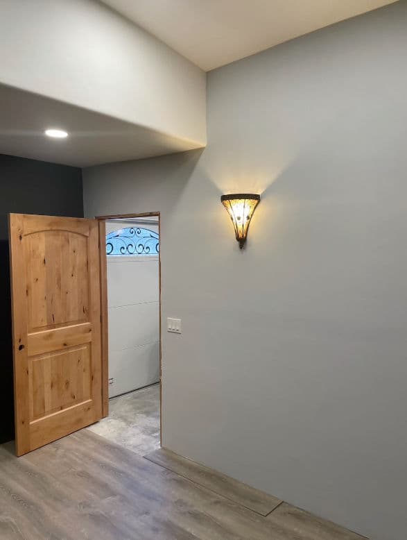 Contemporary room interior featuring a wooden door and wall sconce lighting.